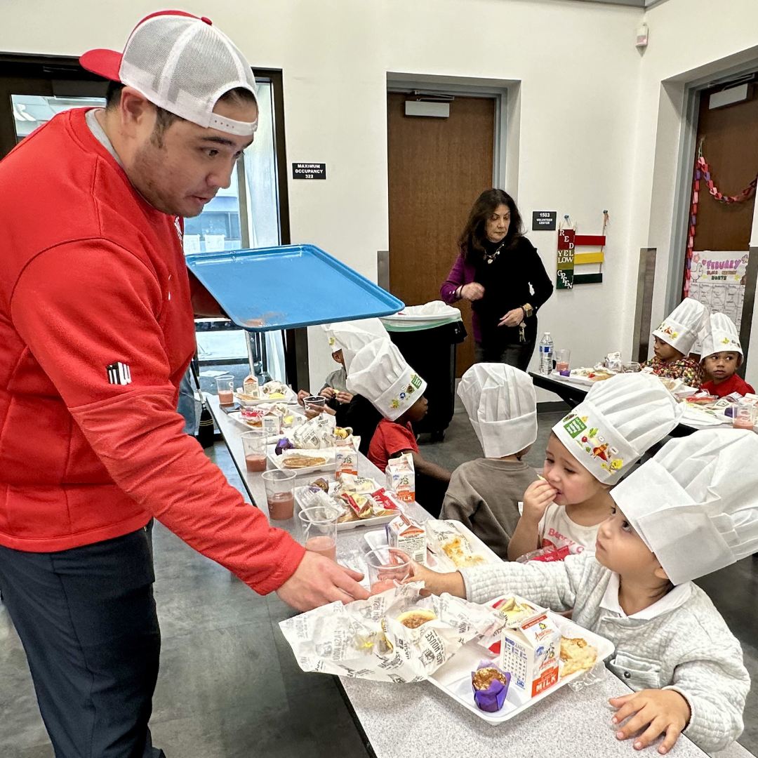 A UNLV Football chef hands a smoothie to a child