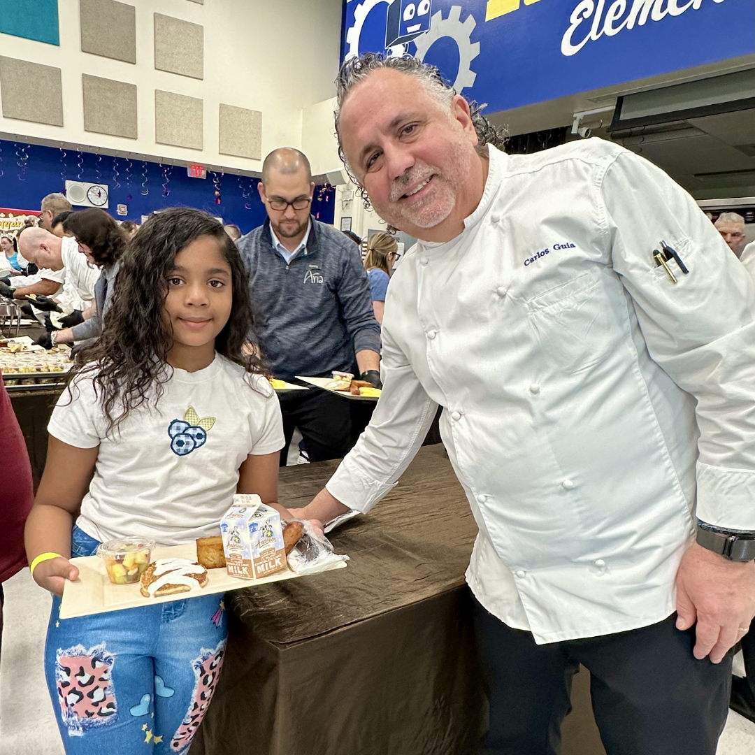 A chef hands a plate of food to a student