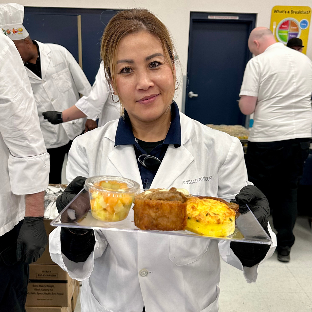 A female chef holds a plate of breakfast