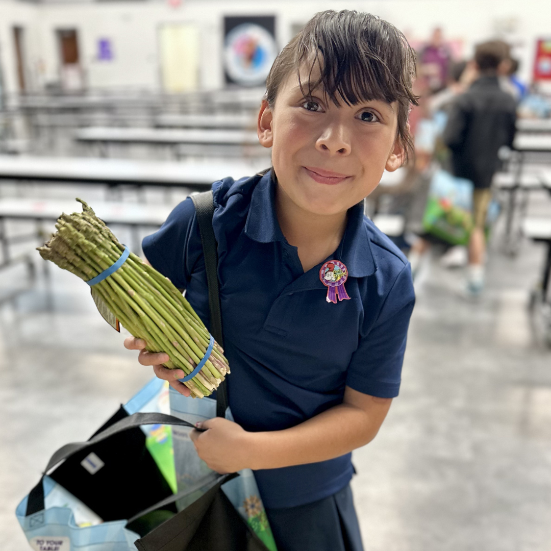 A female student holds up a bunch of asparagus