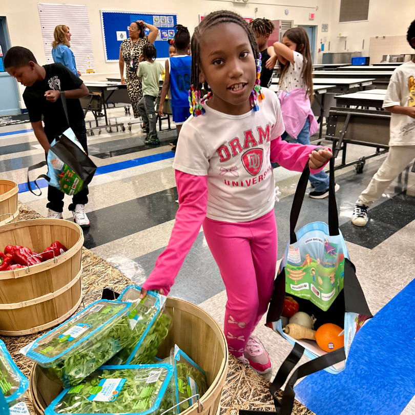 A girl picks arugula out of a basket