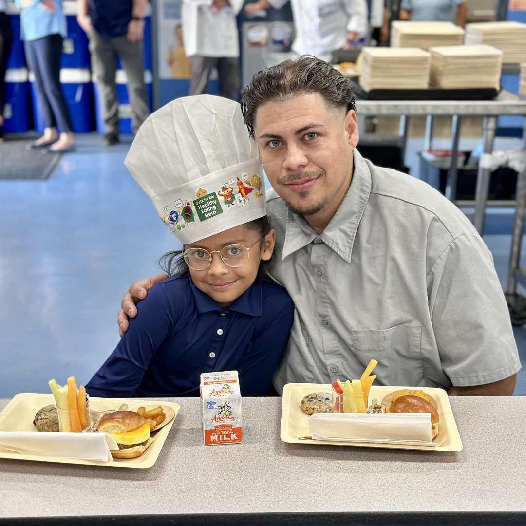 A girl poses for a photo with her dad during breakfast