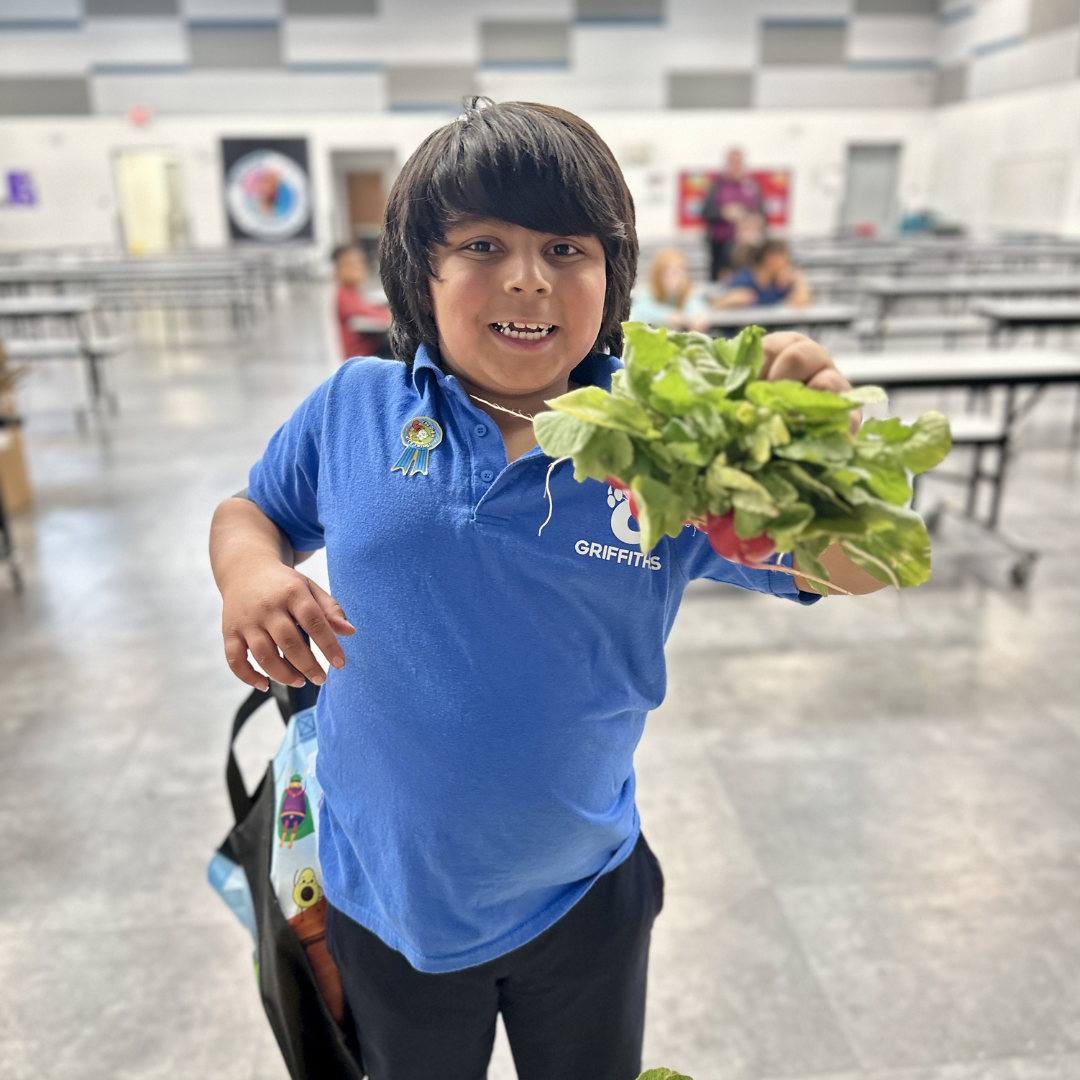 A male student holding a bunch of radishes