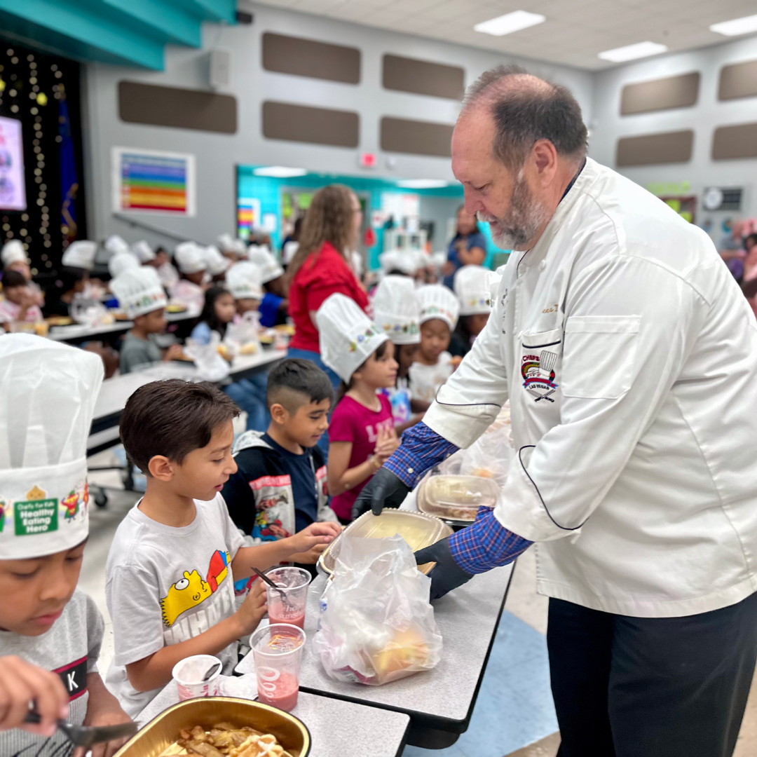 A man in a chef's jacket serves breakfast to a kid