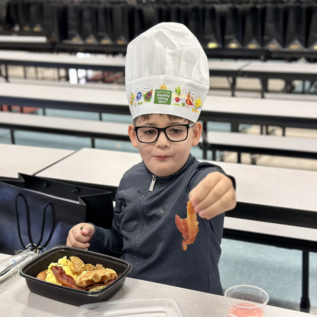 A student holds up a piece of bacon