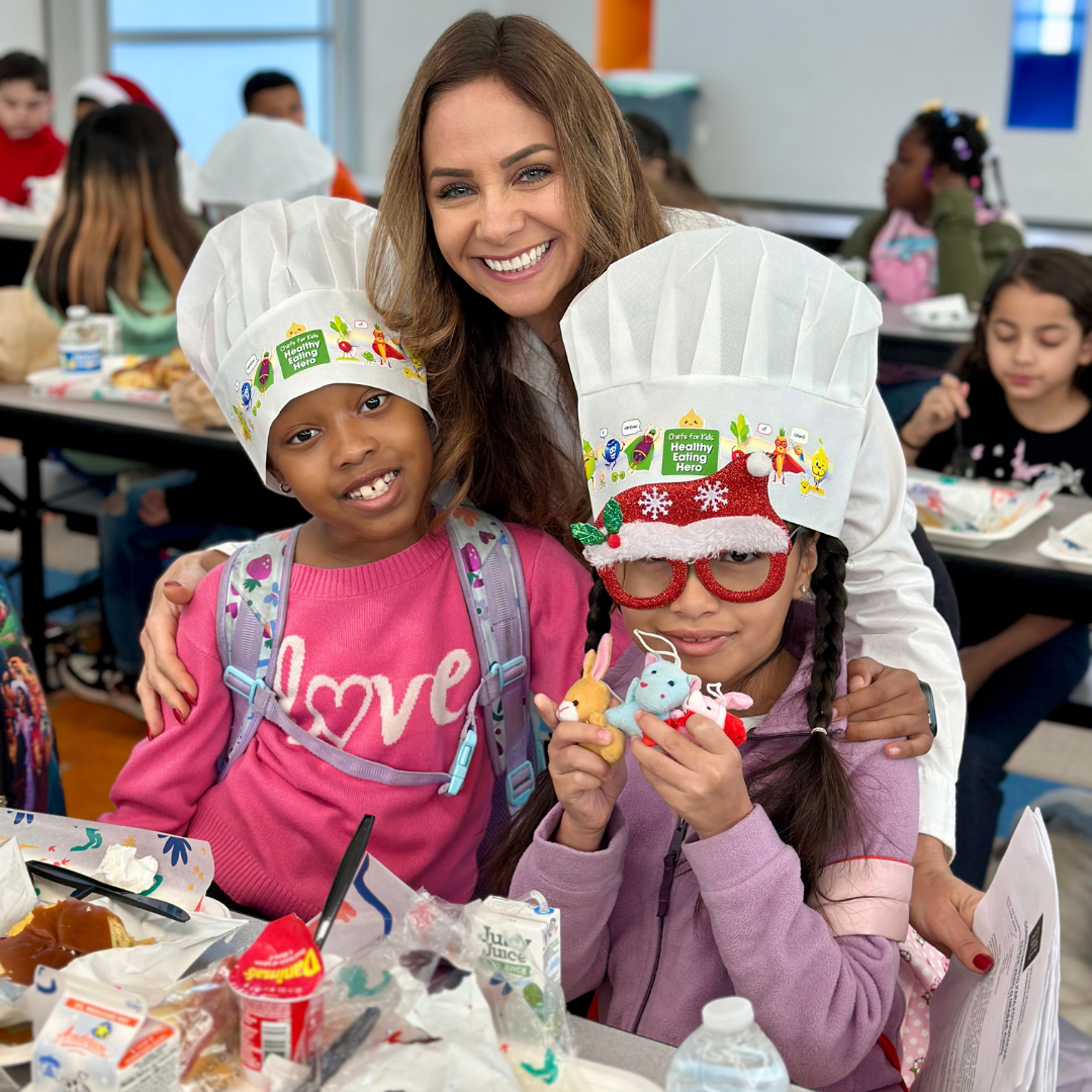 A teacher poses for photos with two young students