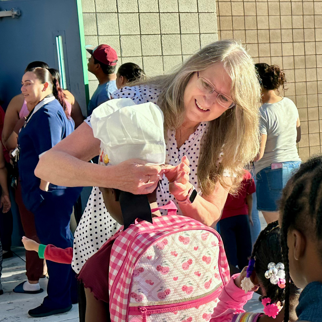 A volunteer puts a chef hat on a kid