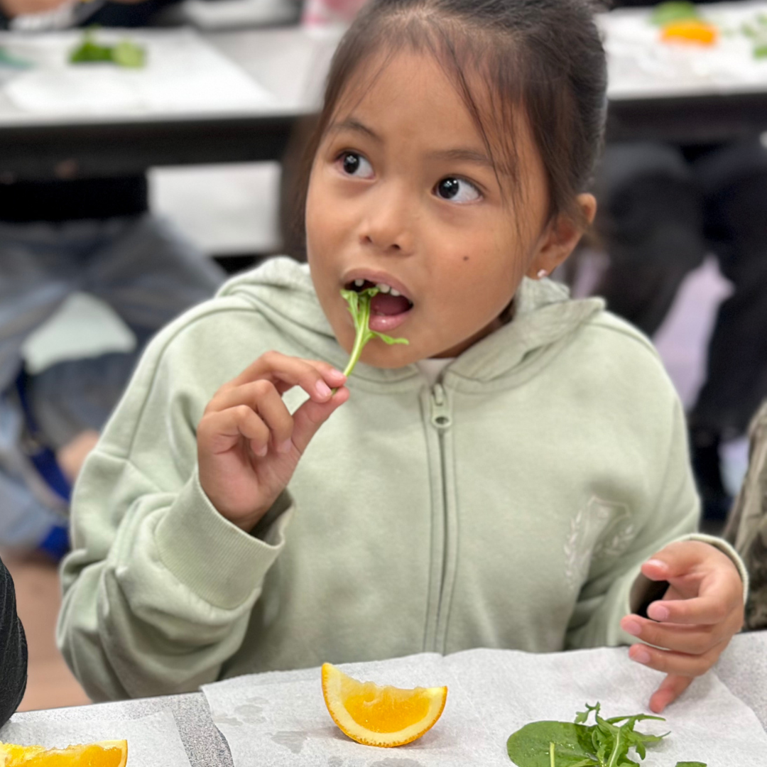 A young female student takes a bite of Arugual at Ries ES