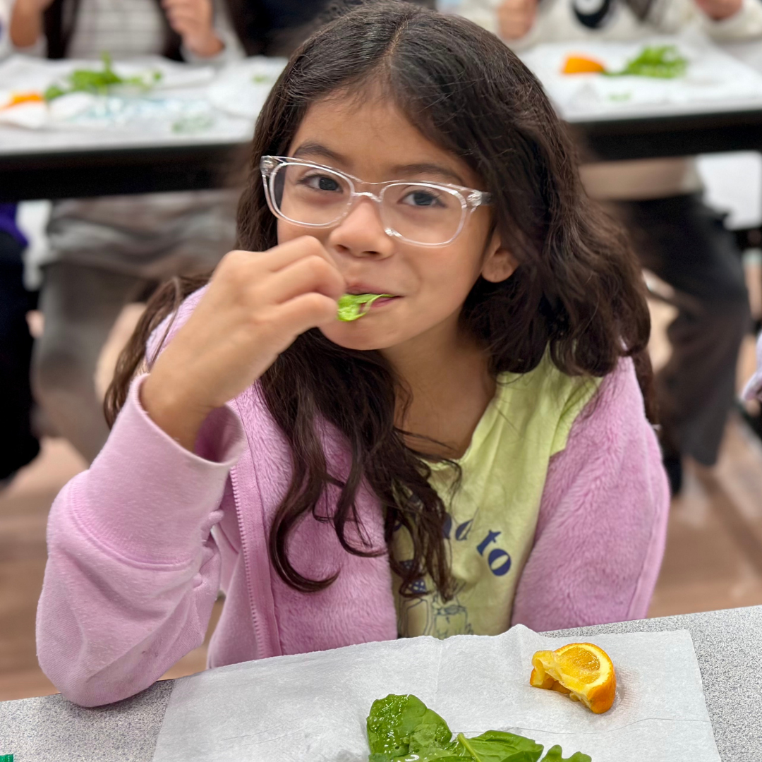 A young girl eats Arugula at Ries ES