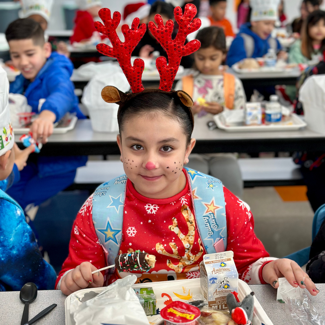 A young kid wears reindeer antlers at breakfast