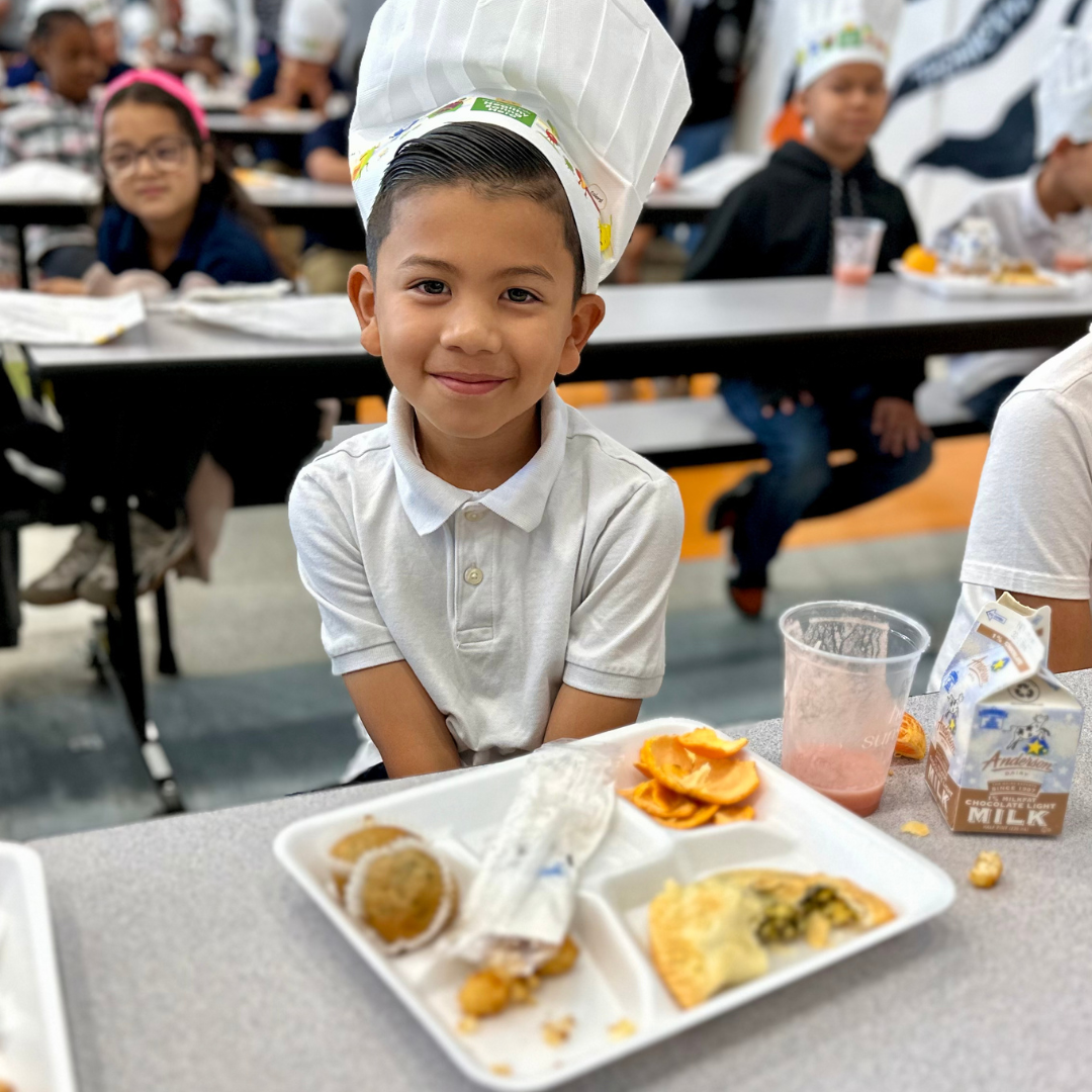 A young male student wearing a chefs hat