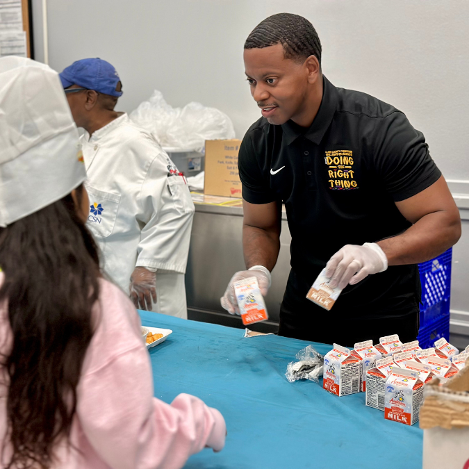 Commissioner McCurdy offers milk to a student