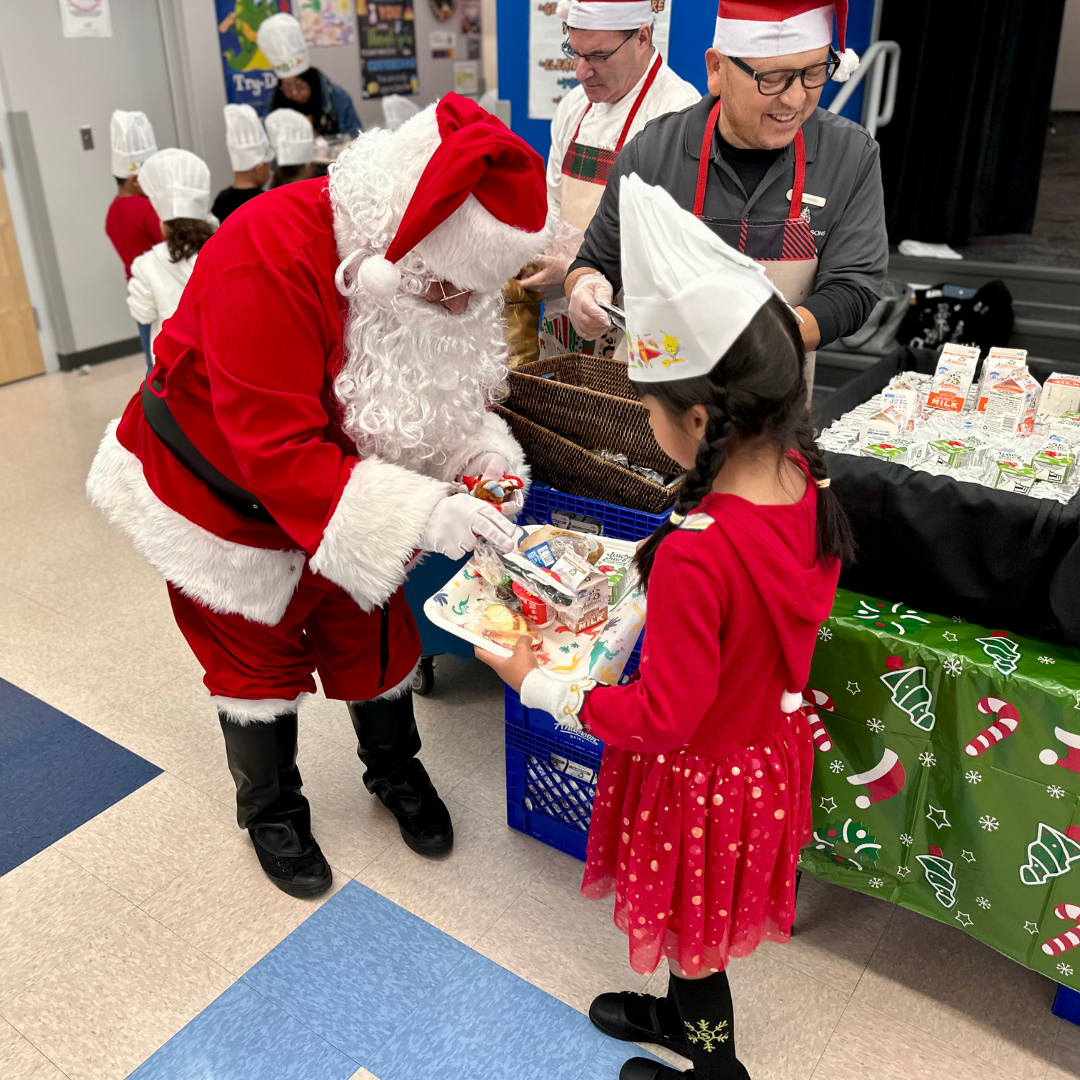 Santa Claus hands a young girl a present