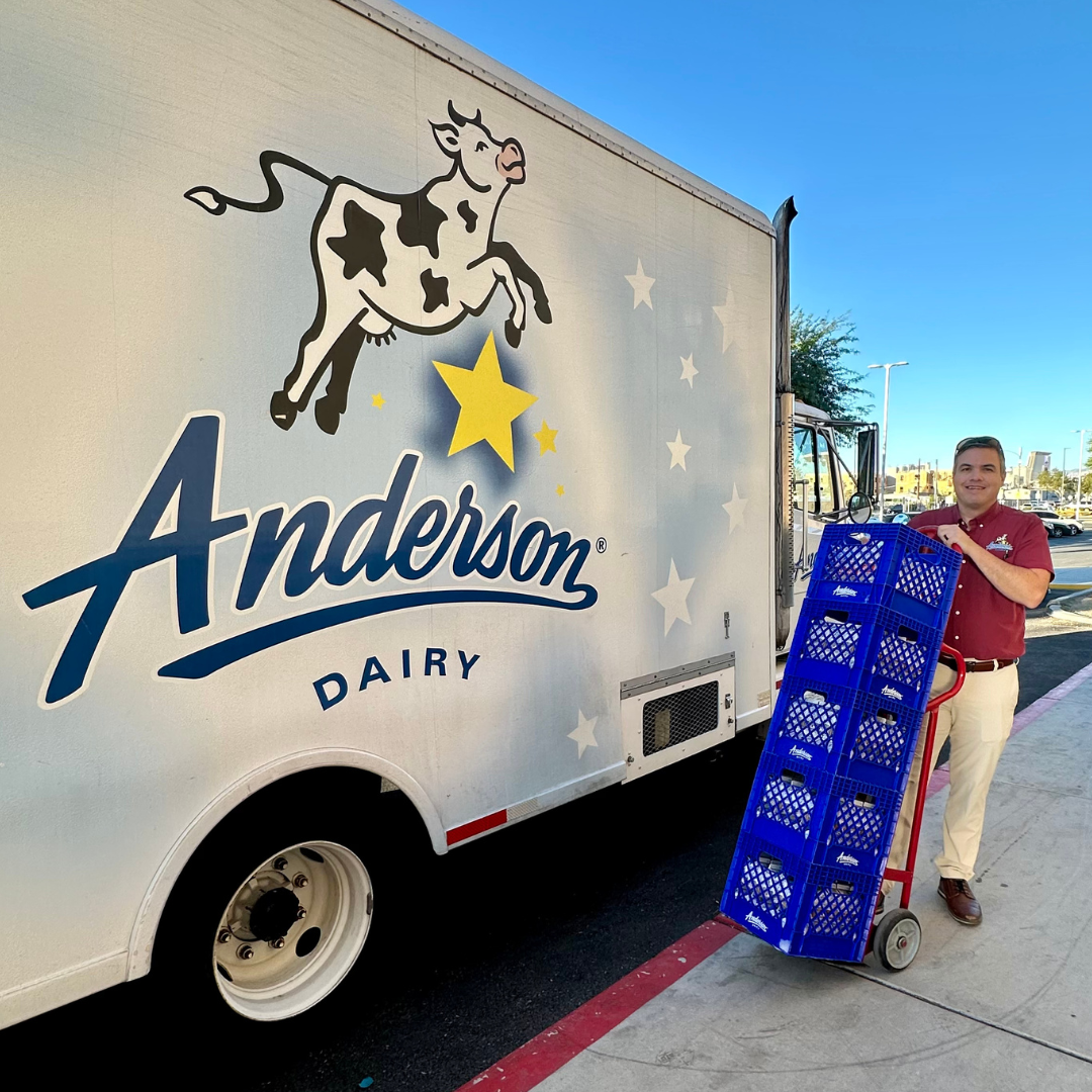 The Anderson milkman holds crates of milk next to the dairy truck