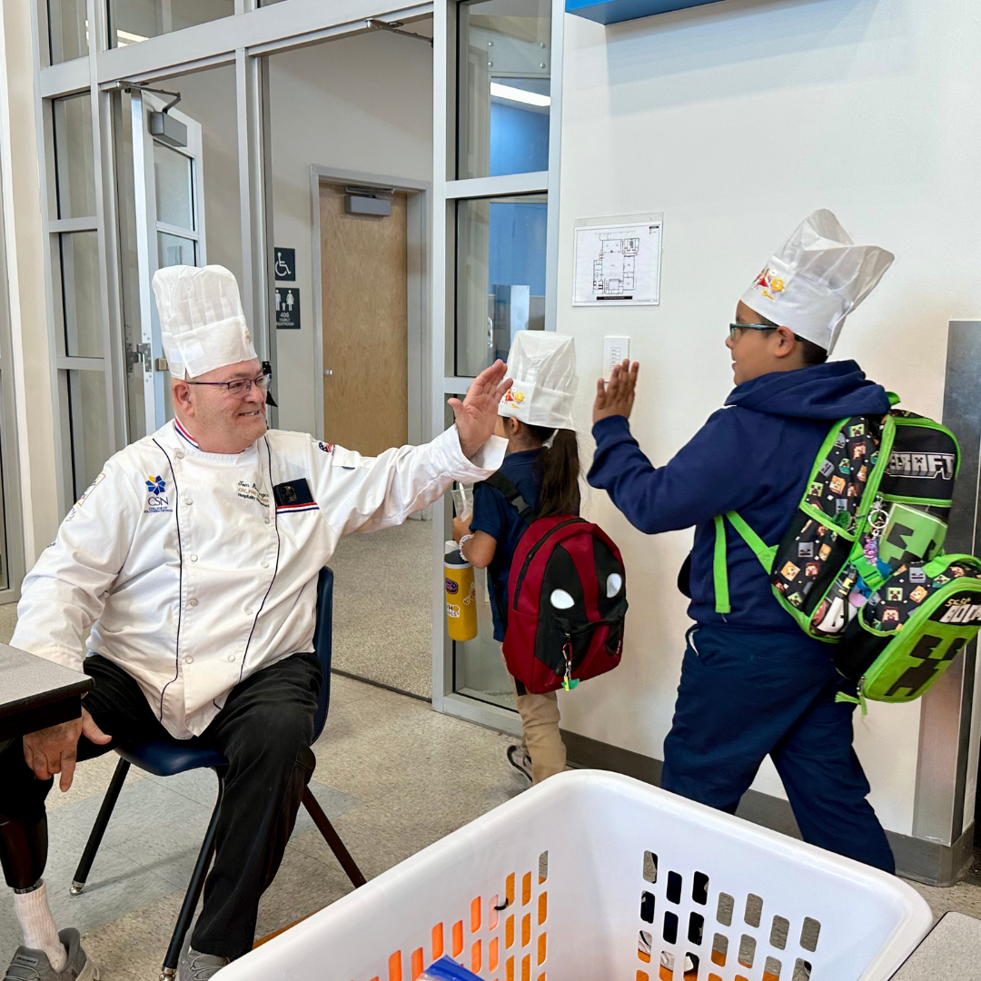 Tom gives high fives to students