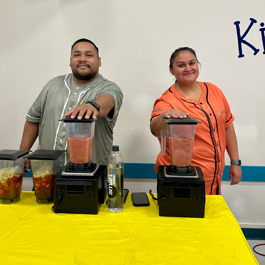 Two Jamba Juice employees hold their hands on blenders making smoothies
