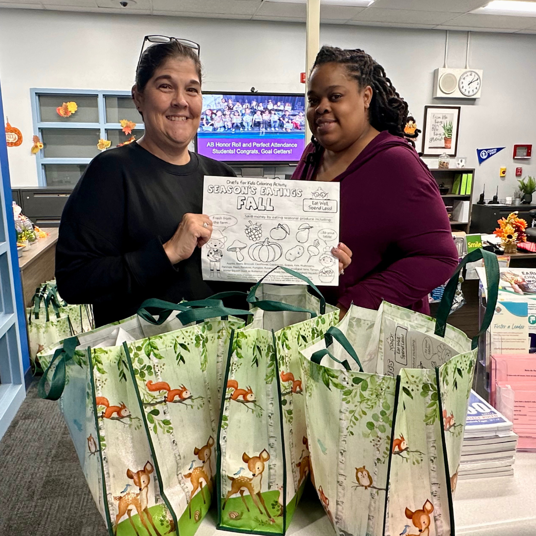 Two educators hold a bag of produce