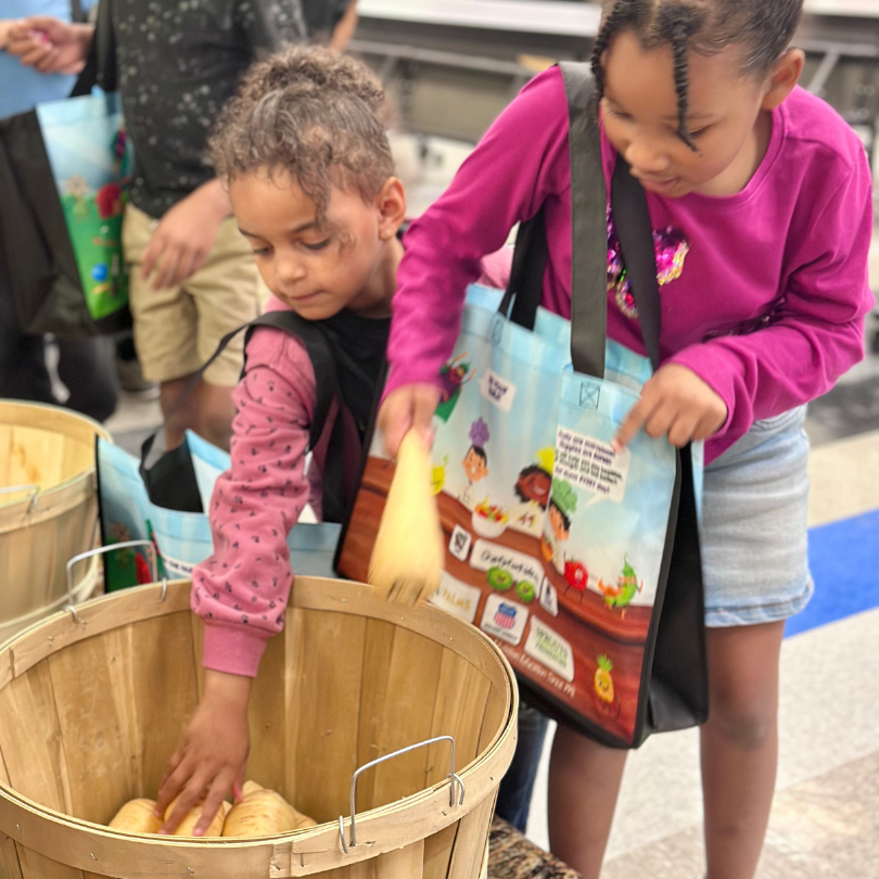 Two girls picking parsnips out of a basket
