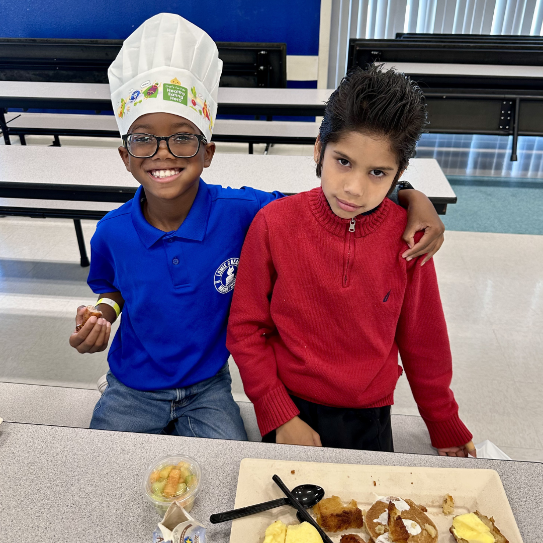 Two kids eat breakfast at a school
